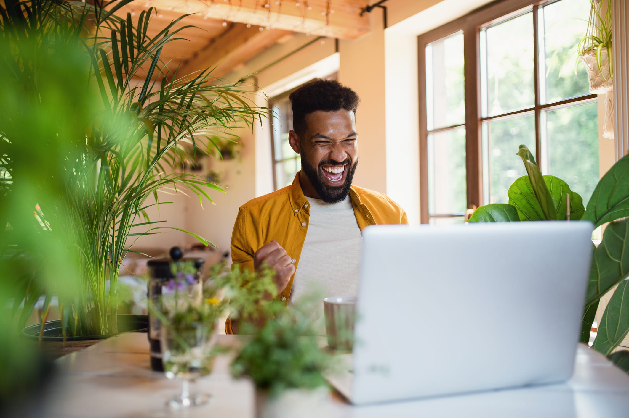 A man smiles widely looking into a laptop.