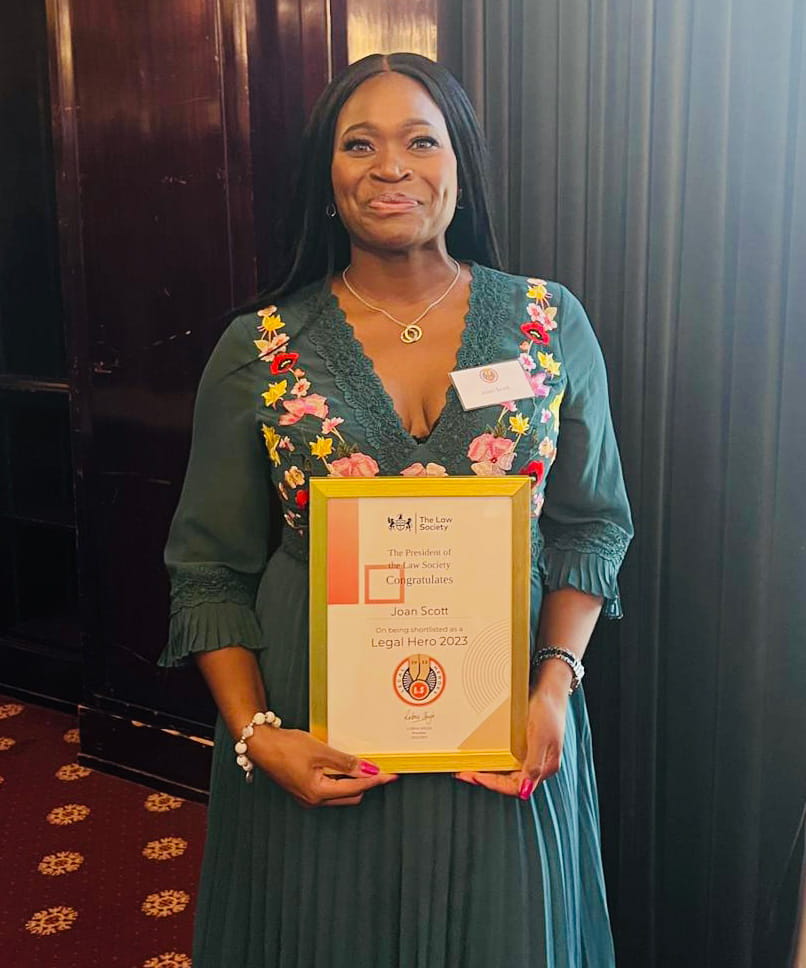 Joan stands in the Law Society holding her Legal Heroes certificate.