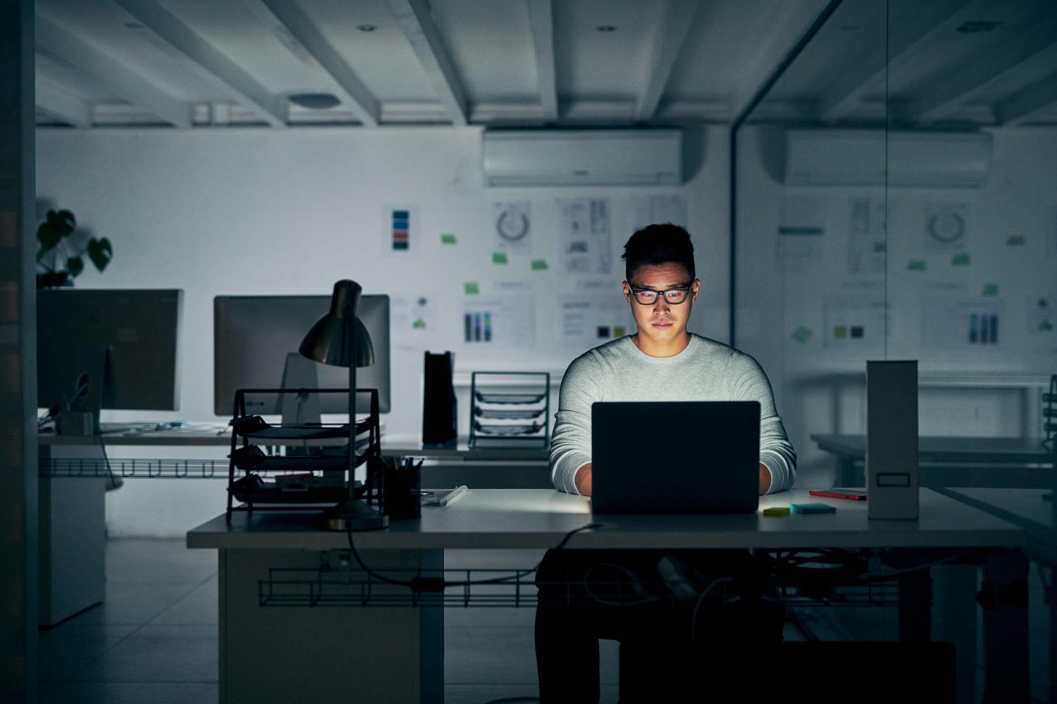 A young man works in the office alone late at night