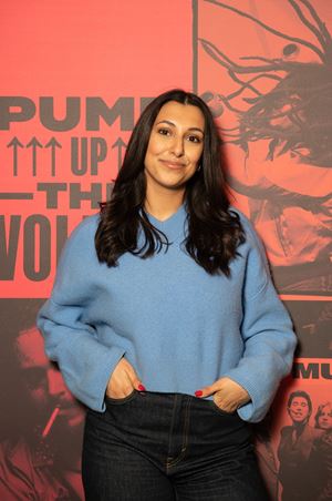Talia Shabatai stands in front of an orange background.