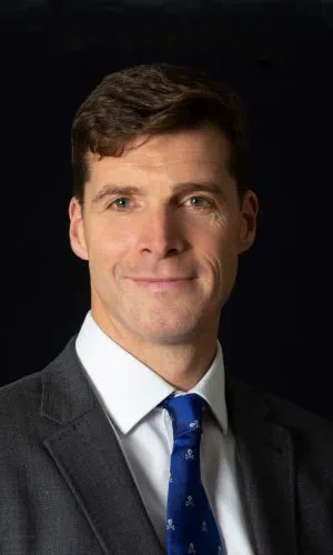 A headshot of a person wearing a suit.