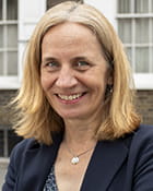 Debra Long is a white woman with shoulder-length straight blonde hair. She is standing outside and smiling, wearing a navy blue jacket and navy patterned shirt.