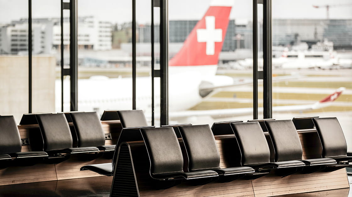 Zurich, Switzerland - October 18, 2020: Empty terminal waiting area at Zurich Airport. A Swiss International Air Lines airplane parked at the gate
