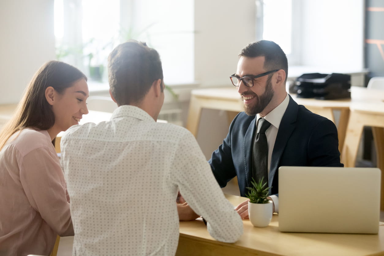 Three people sit at a table in a corporate office.