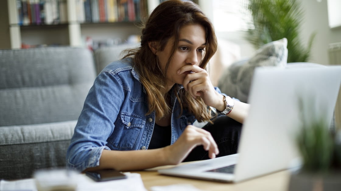 A worried woman looking at a laptop.