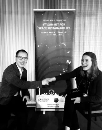 Octavie Ralet shakes hand with Oliver Zhuang Tian on the panel stage at the Summit for Space Sustainability in 2022