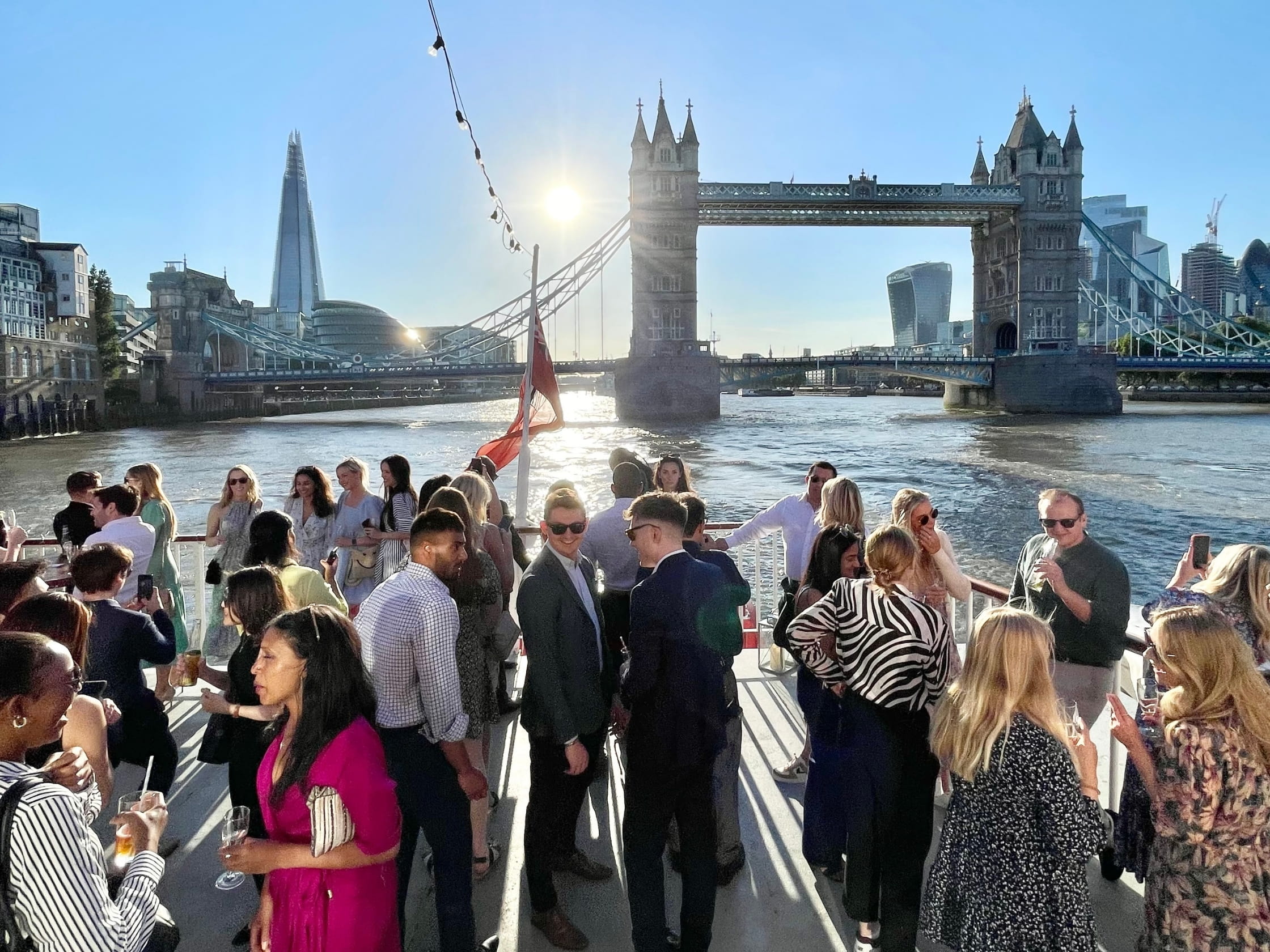 A group of young professionals at a networking event in front of Tower Bridge.