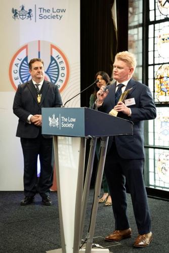 Solicitor Kevin McManamon accepting his Legal Hero Award at the 2024 ceremony at the Law Society, standing in background are former Law Society presidents Nick Emmerson and Lubna Shuja