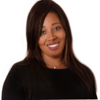 Jacqui is a black woman. She is smiling in front of a plain white background.