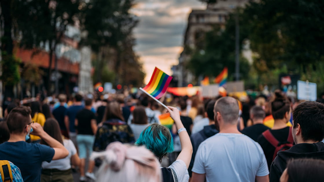 A diverse group of people holding up flags at a Pride march.