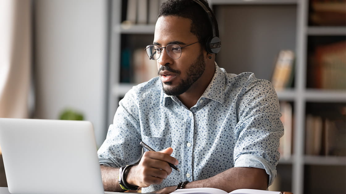 Trainee working on laptop and writing in notepad