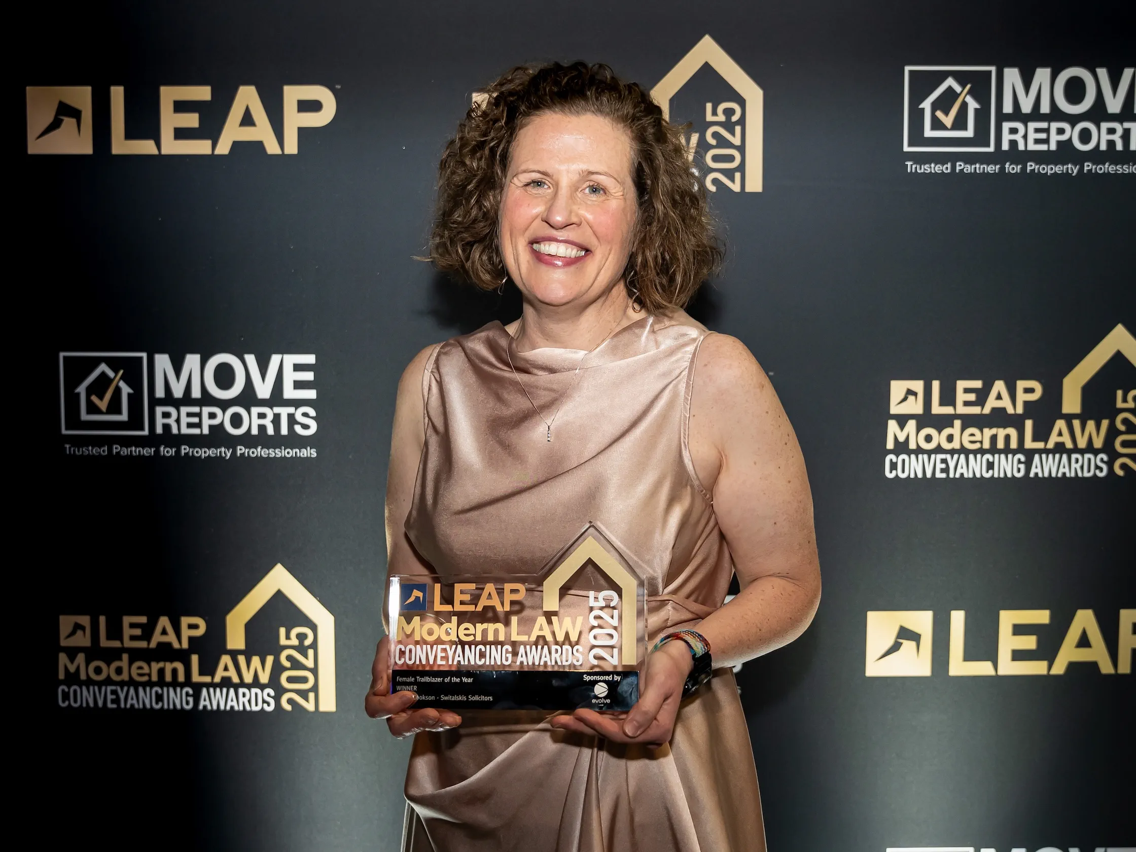 A woman in a metallic dress holds an award.