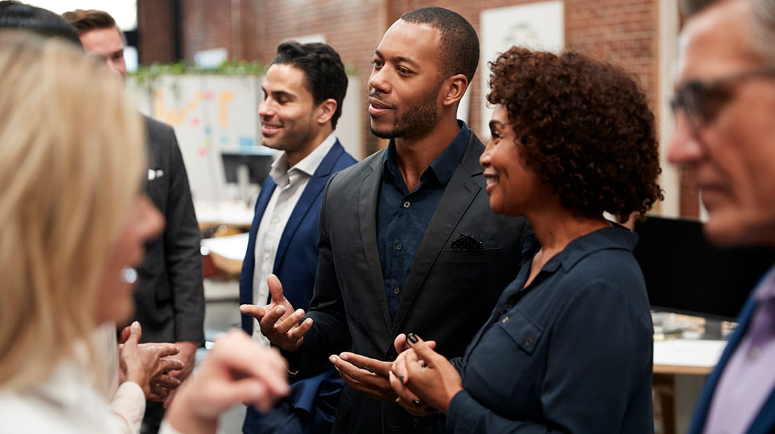 A group of professionals talking casually in an office setting.