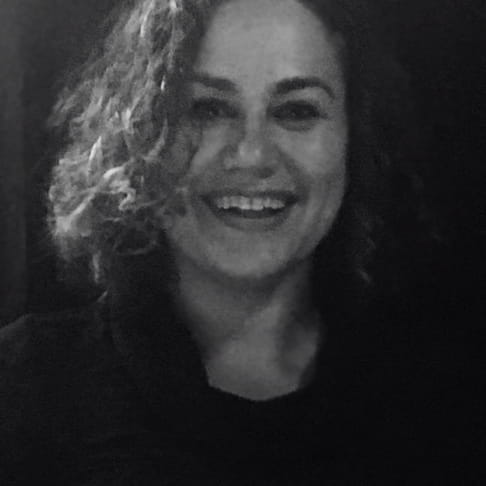 Ayesha Siddiqi is a woman with curly hair, smiling and the camera (black and white image)