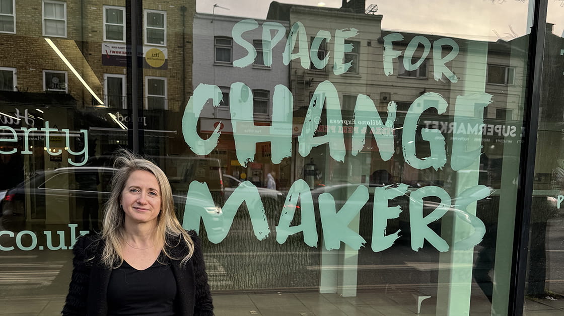 Anne-Marie Irwin stands in front of an office window with the words "Space for change makers".
