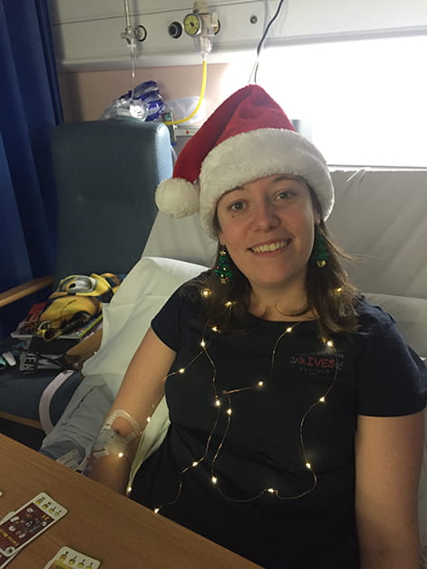 Solicitor Alexandra Wilson smiles in a hospital bed whilst wearing a Santa hat