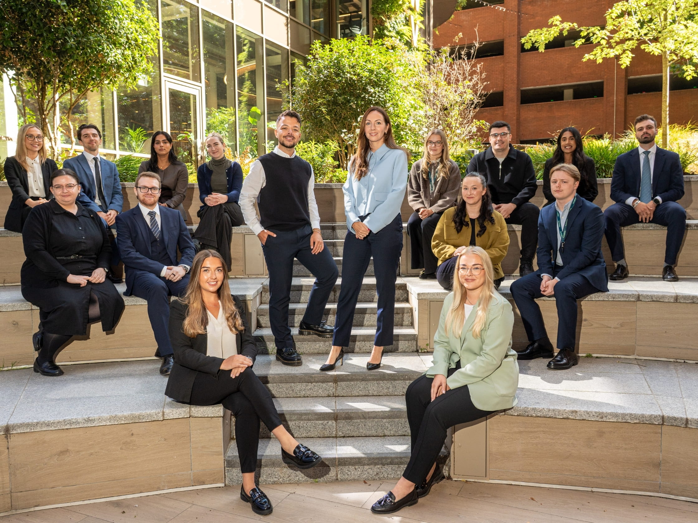 Amy Clowrey standing on steps with a colleague, with a group of people sitting on steps.