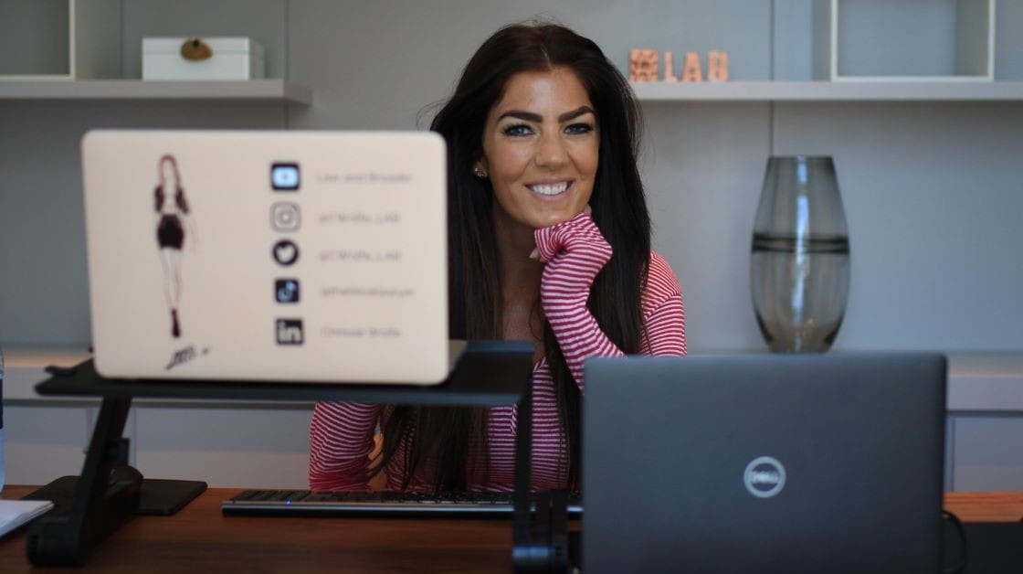 Solicitor and influencer Chrissie Wolfe sits at her desk with two laptops in front of her