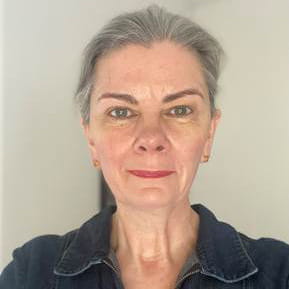 Claire is a woman with grey hair, she is smiling into the camera. 