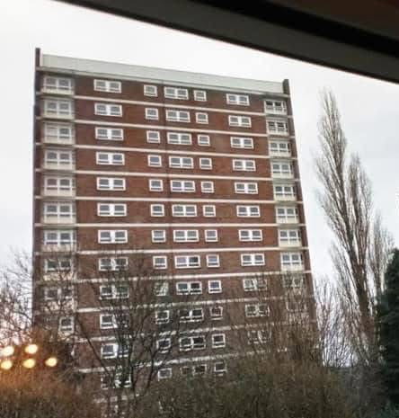 Tower block of flats seen through a window on an overcast day in winter