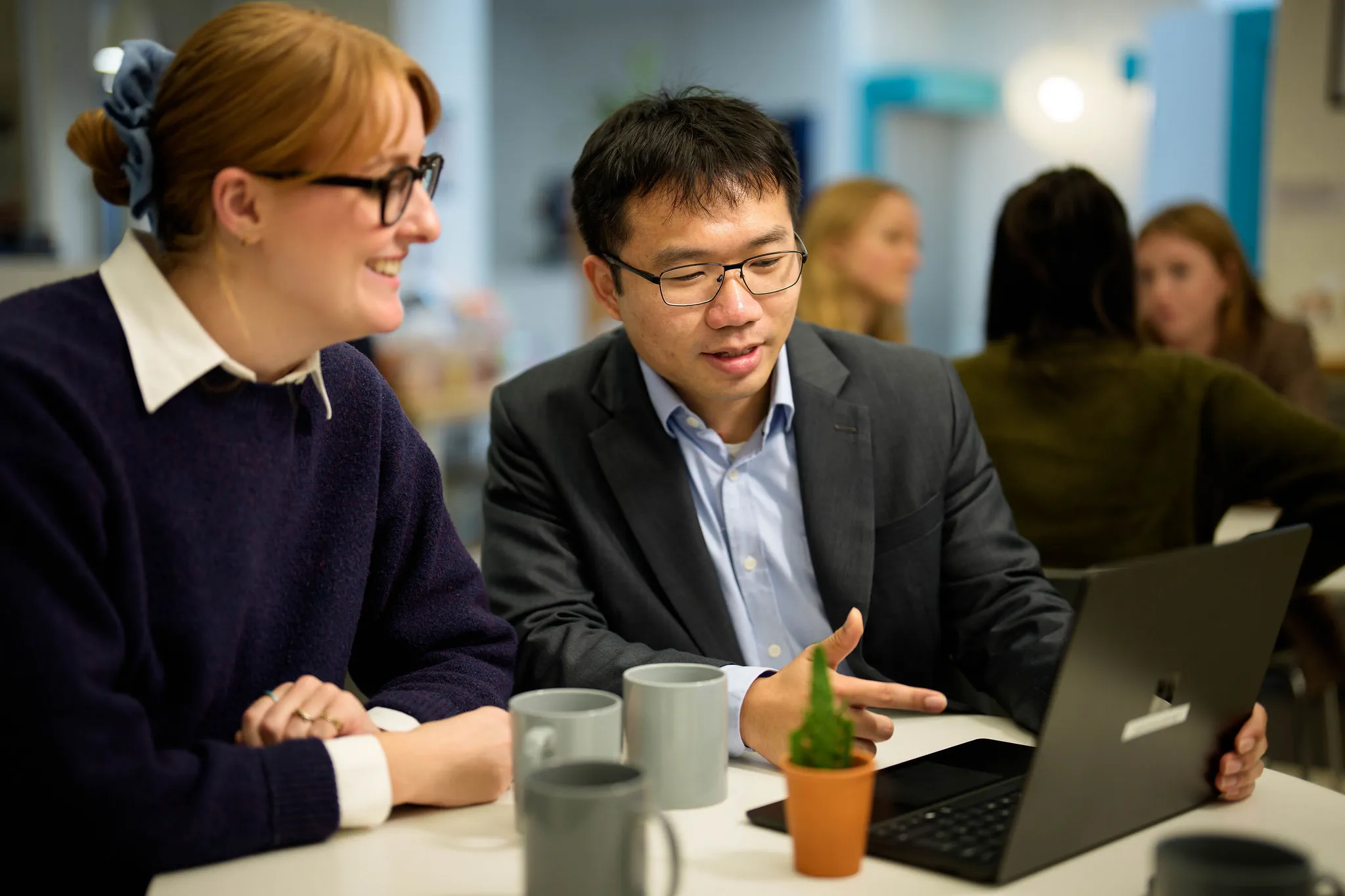 Two solicitors smiling and looking at a laptop
